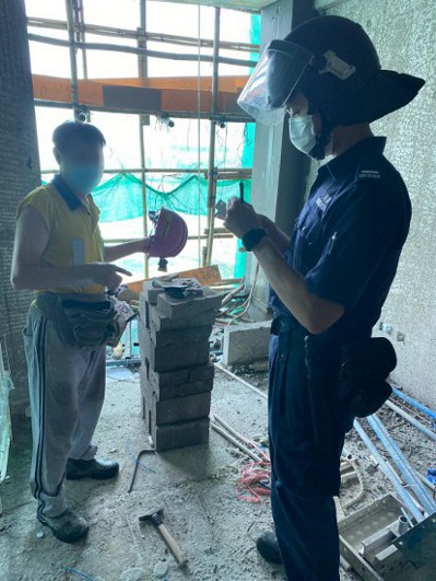 Photo shows ImmD officers conducting proof of identity checks in a construction site.
