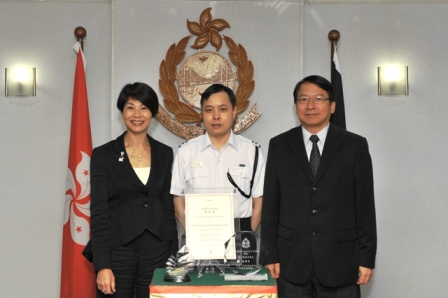 香港旅遊發展局副總幹事雷詠閒（左）及入境事務處處長陳國基（右）今日（四月二十六日）頒發獎狀和紀念品予「最有禮貌入境管制人員」康祺英。