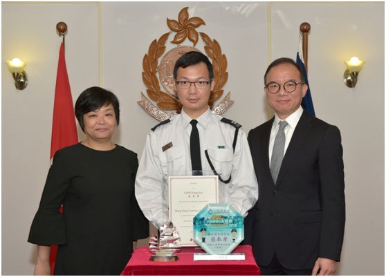 The Senior Manager of Corporate Communications of the Hong Kong Tourism Board, Ms Jane Ha (left), and the Director of Immigration, Mr Tsang Kwok-wai (right), present awards and a souvenir to the most courteous Immigration control officer, Mr Choi Fung-hau, today (April 12).