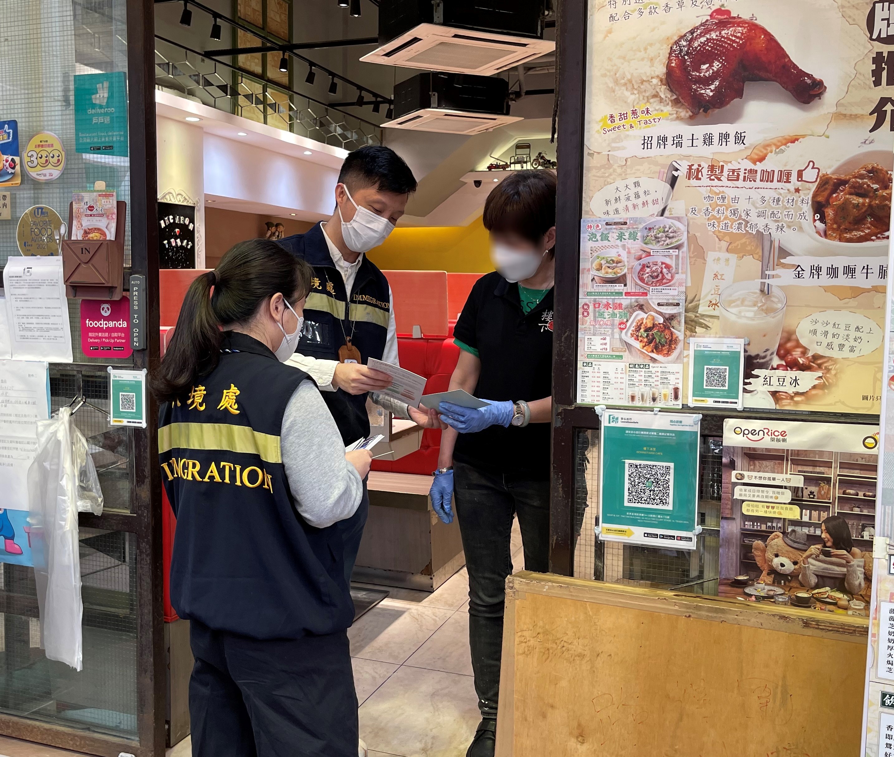 入境事務處人員向食肆職員派發「切勿聘用非法勞工」的宣傳單張。
