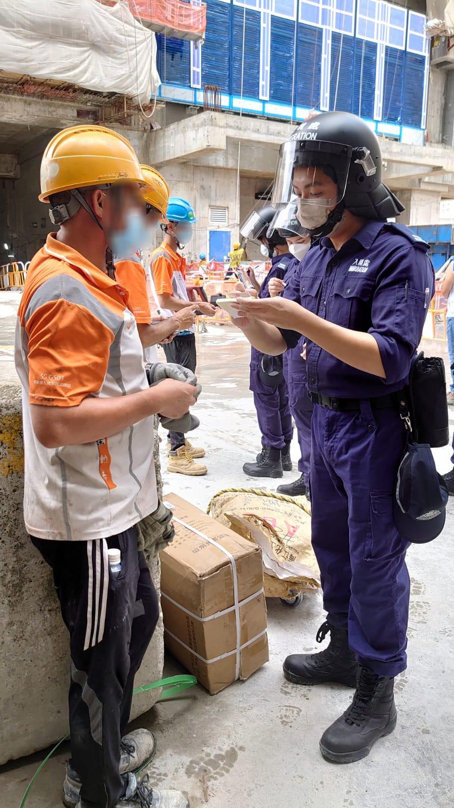 Photo shows ImmD officers conducting proof of identity checks.