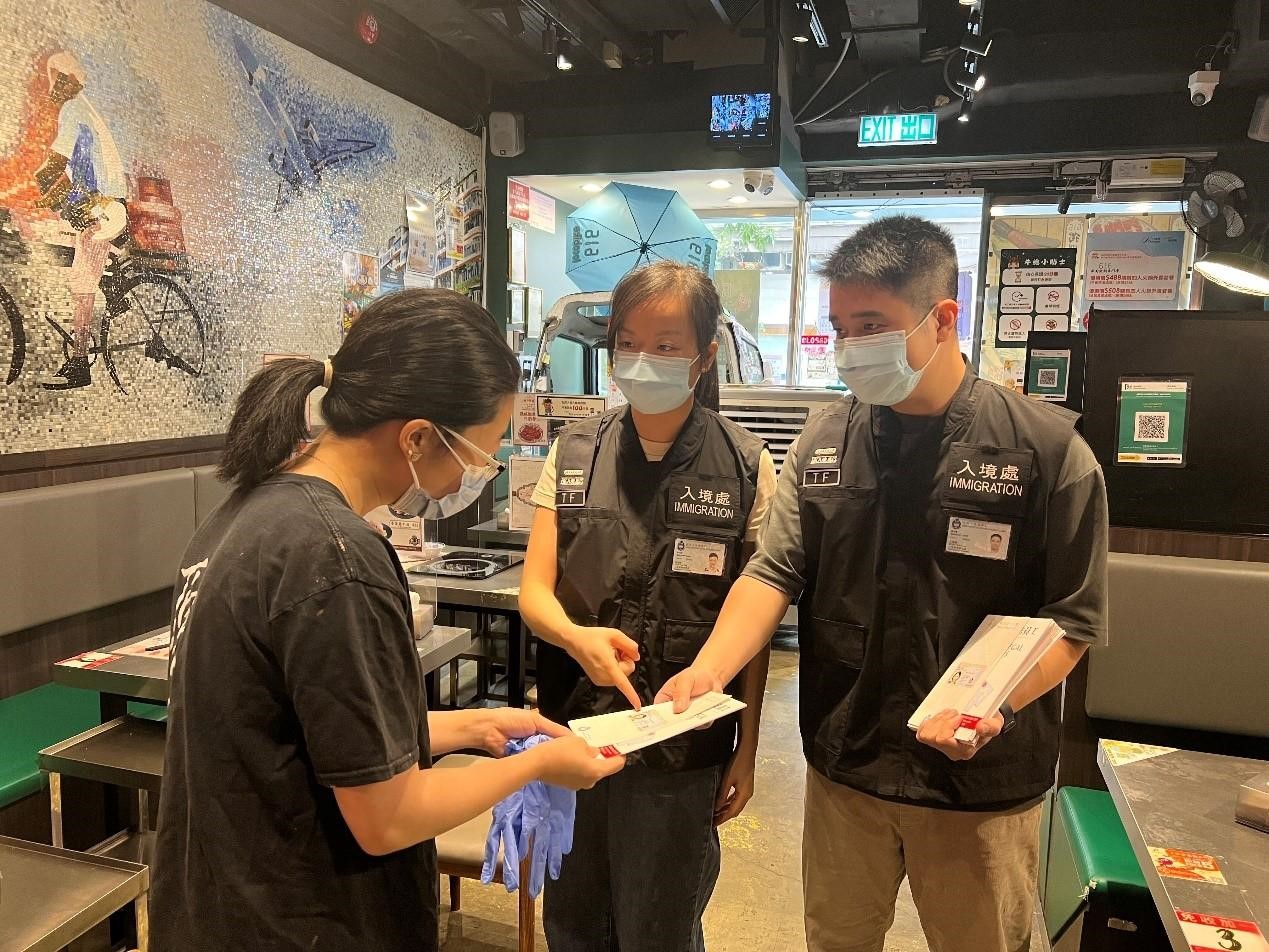 Photo shows Immigration investigation sub-division officers distributing "Don't Employ Illegal Workers" leaflets to restaurant staff.
