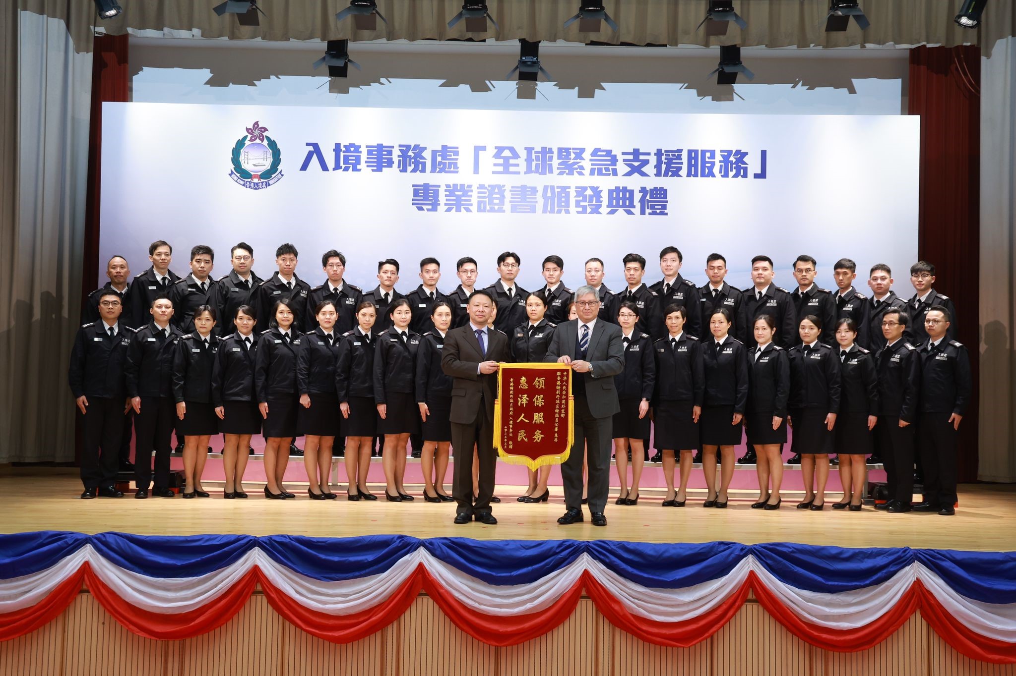 The Director of Immigration, Mr Au Ka-wang (front row, right), presents a silk banner to the Deputy Director-General of the Consular Department, Office of the Commissioner of the Ministry of Foreign Affairs in the Hong Kong Special Administrative Region, Mr Zheng Jie (front row, left), at the certificate presentation ceremony for 