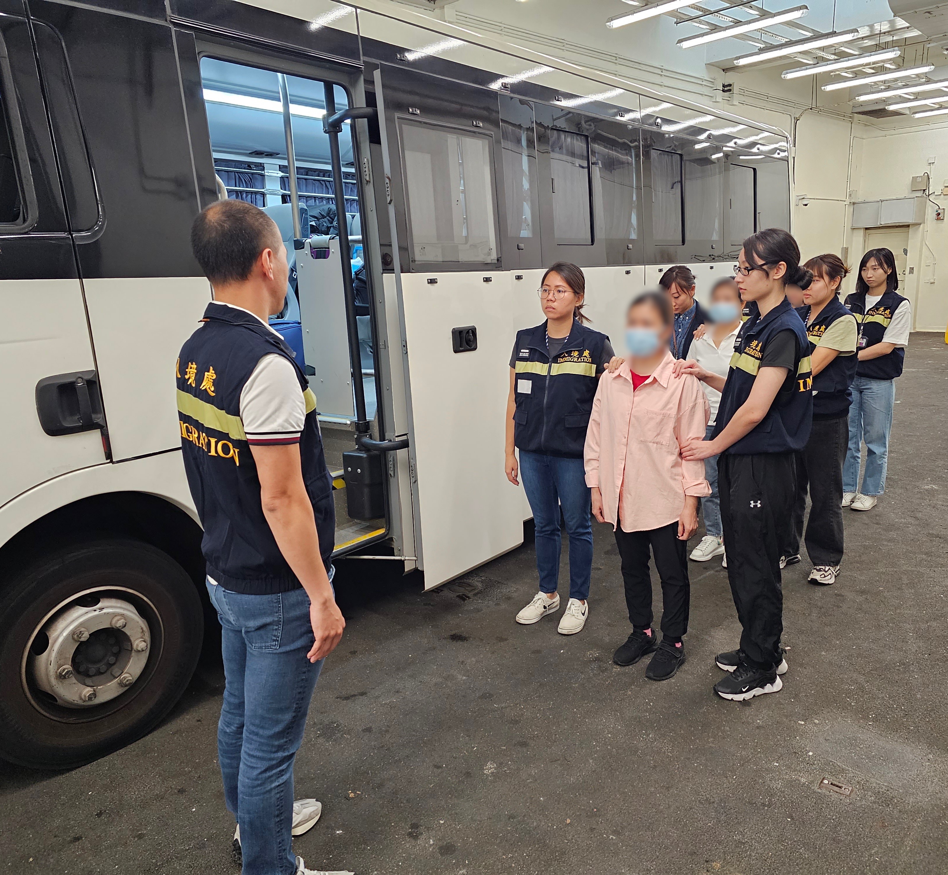 Photo shows removees being escorted by ImmD officers to proceed from the detention place to the airport.
