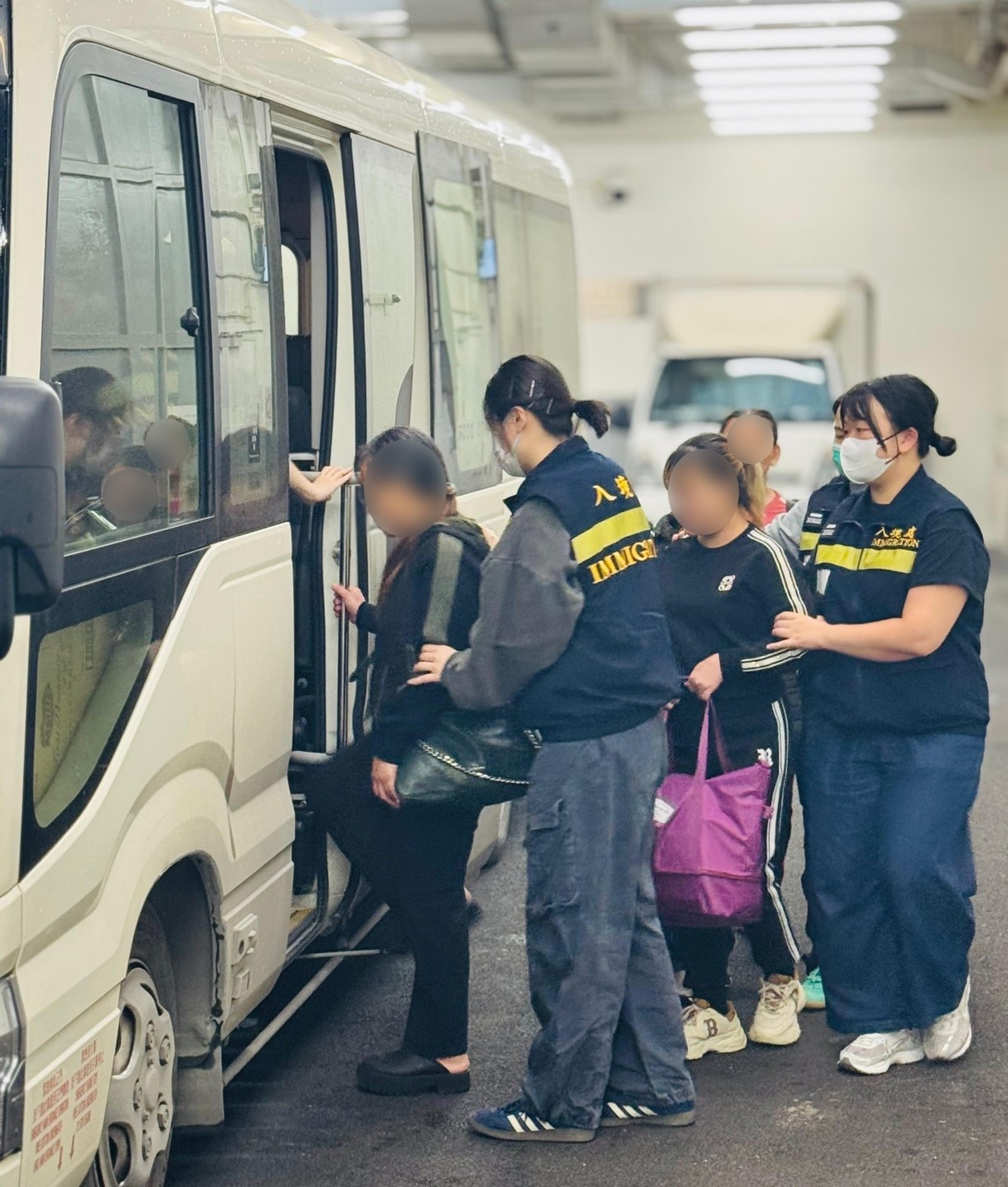 圖示被遣返人士在入境處人員押送下離開羈押地點前往機場