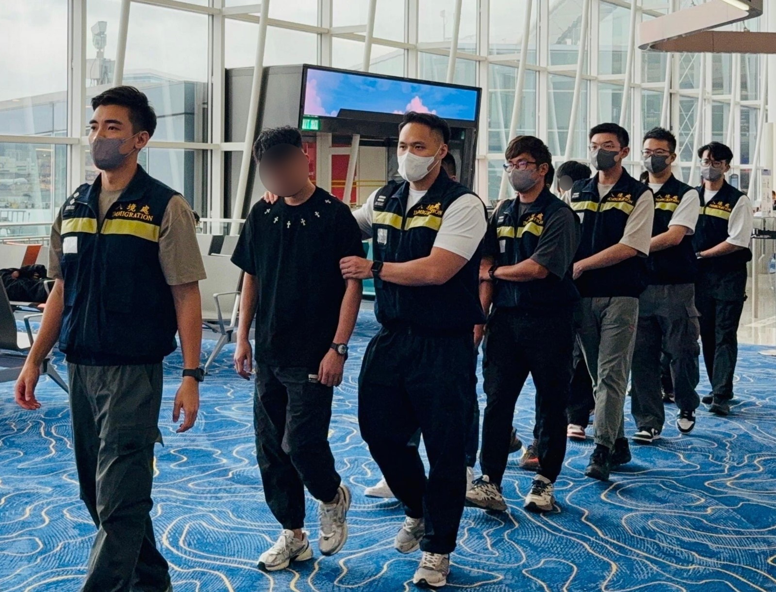 圖示被遣返人士在入境處人員押送下離港