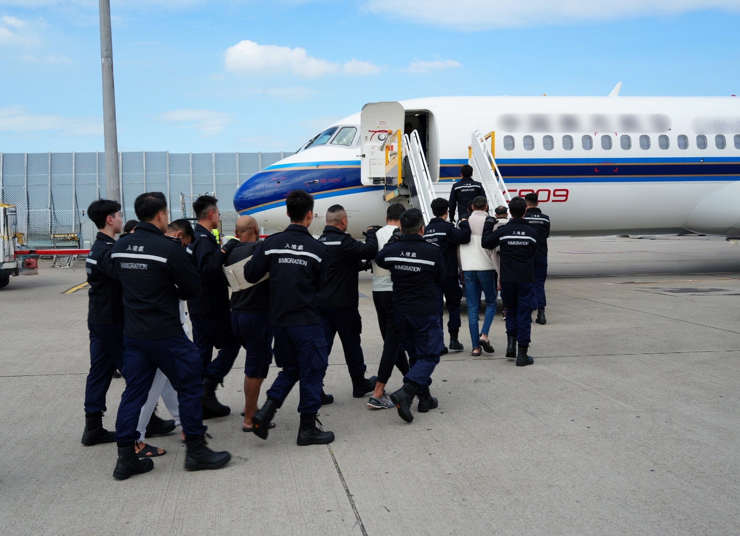 圖示被遣返人士在入境處人員押送下離港