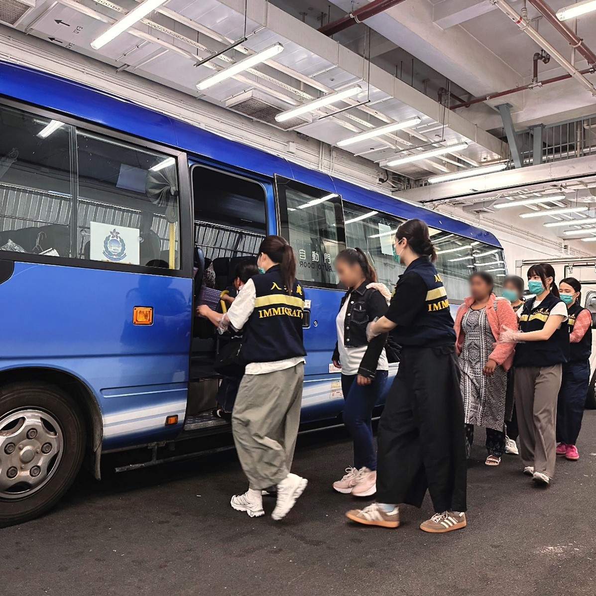 Photo shows removees being escorted by ImmD officers to proceed from the detention place to the airport
