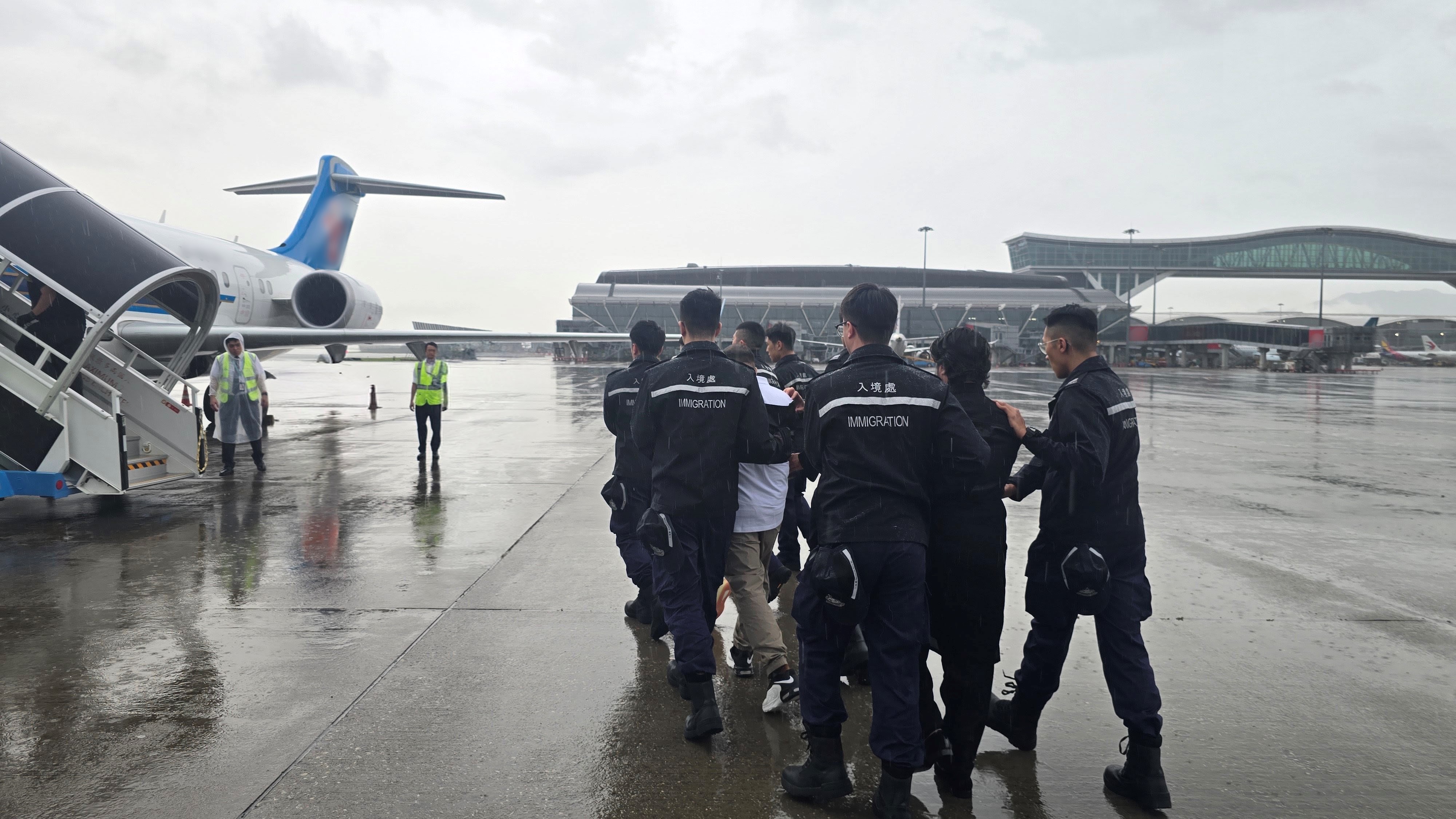Photo shows removees being escorted by ImmD officers to depart from Hong Kong