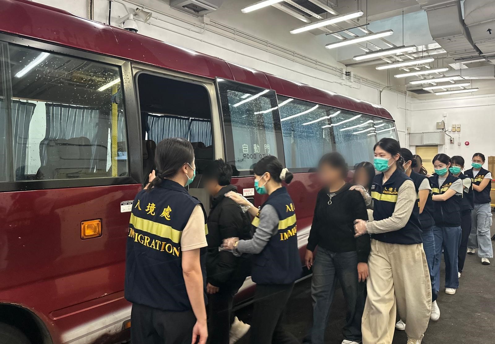 图示被遣返人士在入境处人员押送下离开羁押地点前往机场
