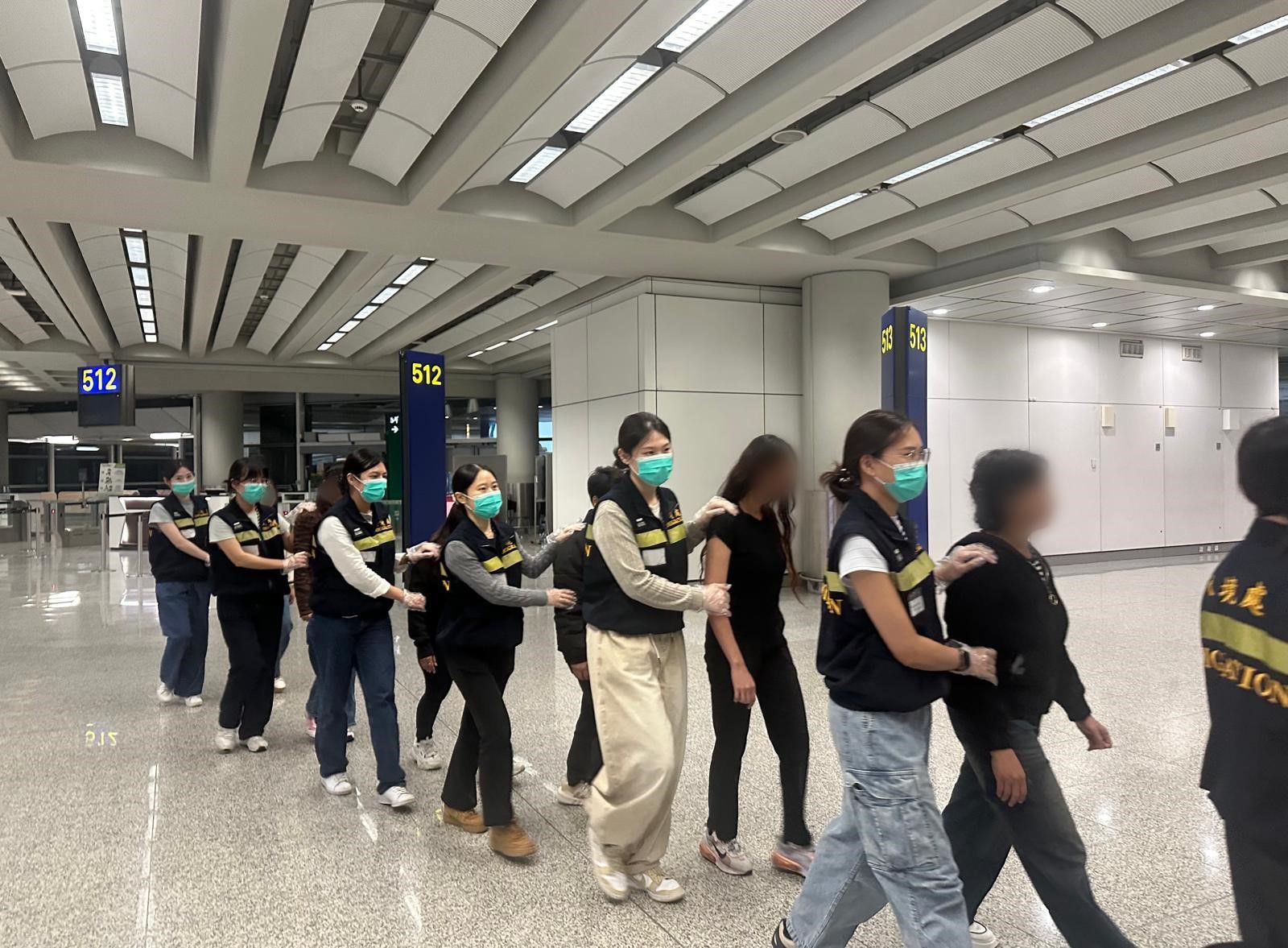 图示被遣返人士在入境处人员押送下离港
