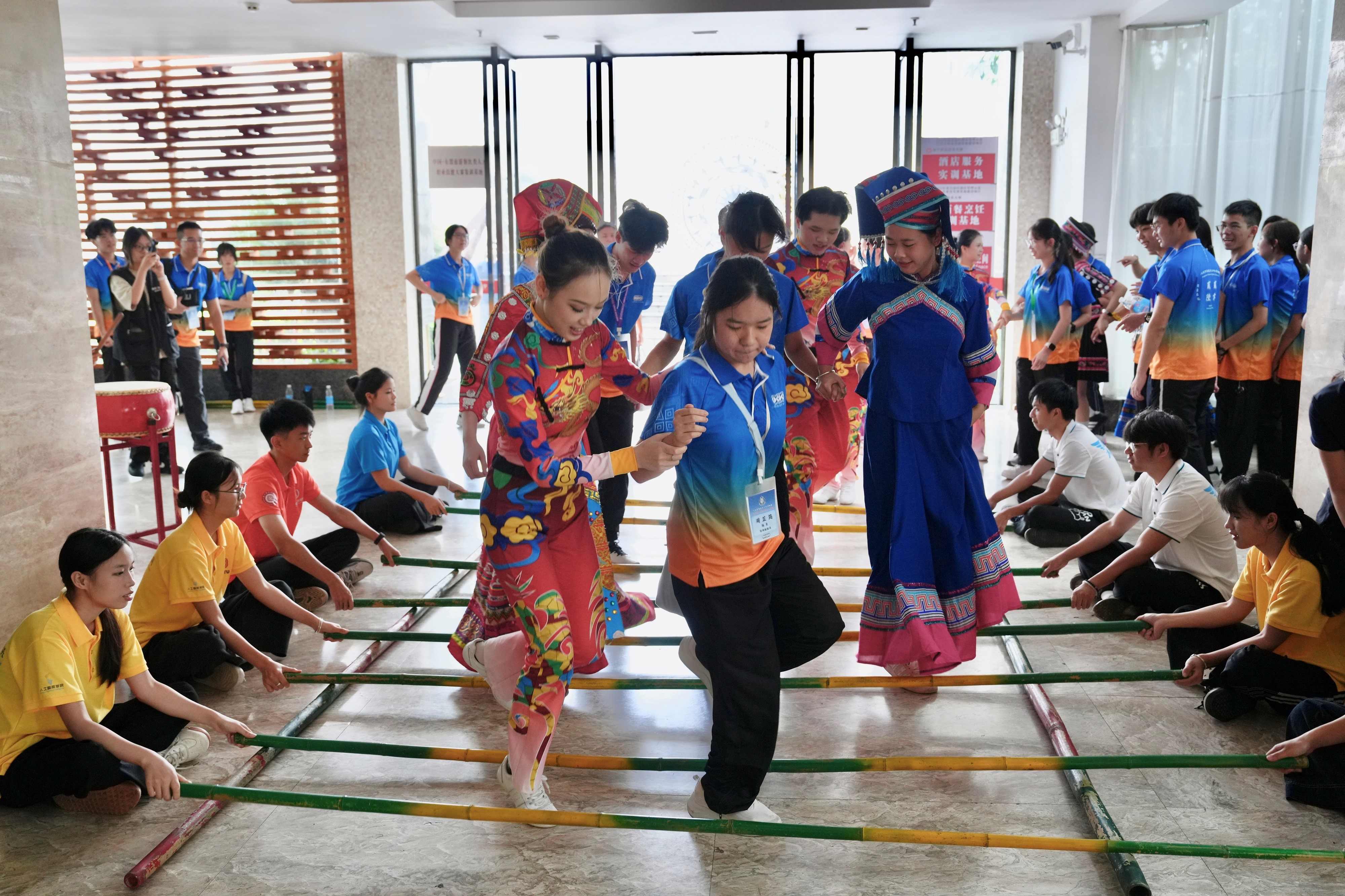 Members of the IDYL Belt and Road Exploration Tours: Guangxi Tour conduct exchanges with local young people and experience the traditional Zhuang bamboo dance at Nanning Vocational and Technical University on July 21.